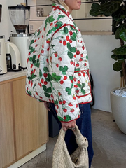 Person wearing a quilted jacket with strawberry pattern in a kitchen setting