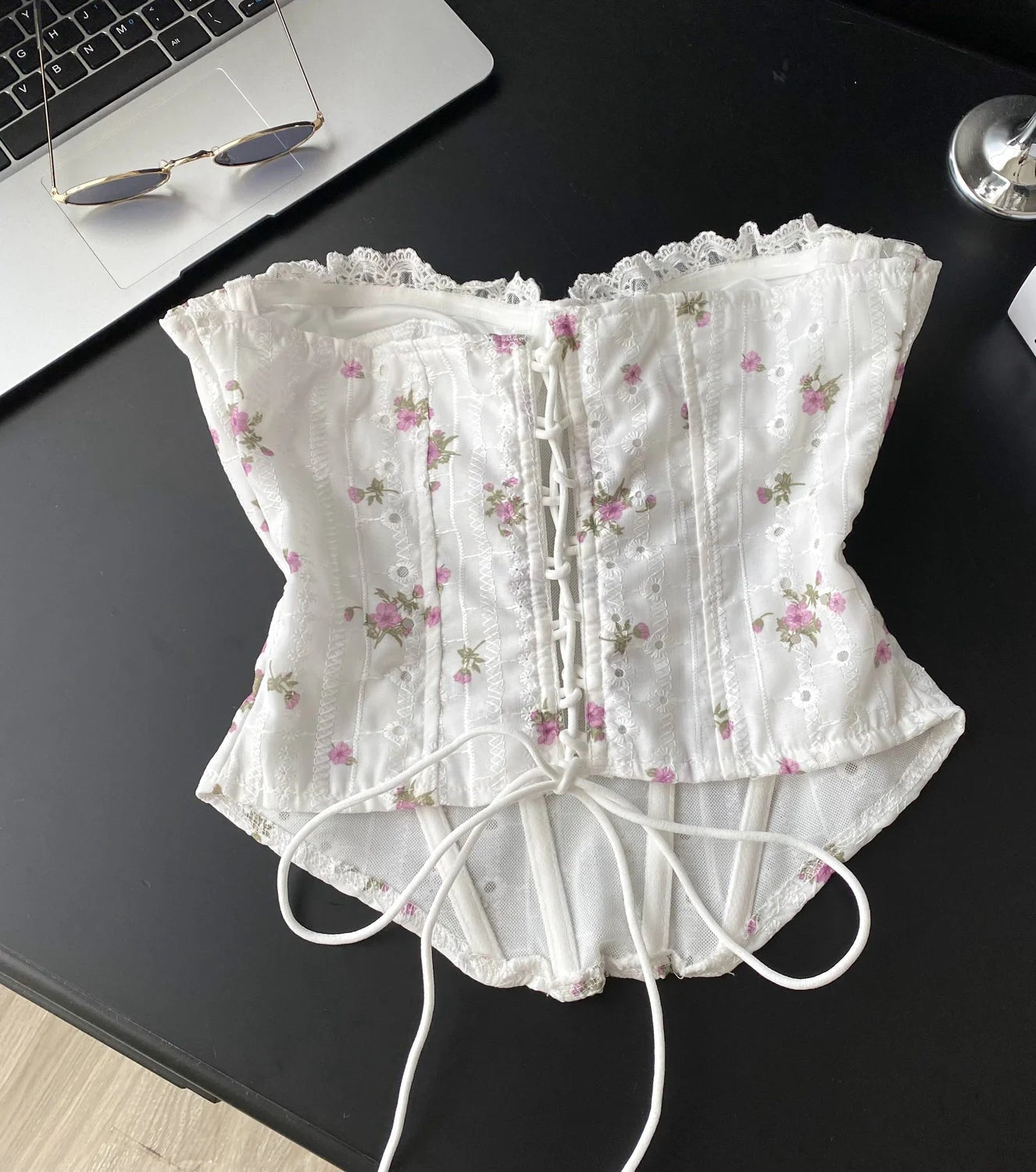 White lace corset with floral patterns on a black surface
