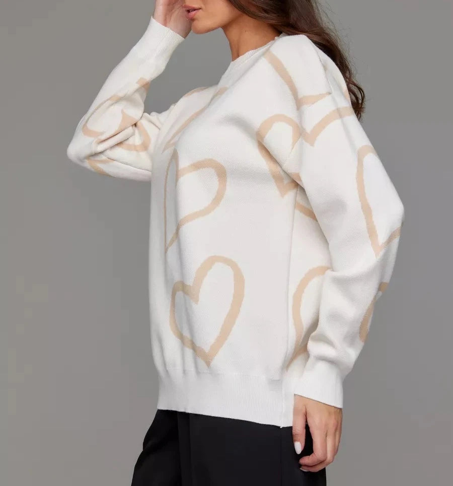 White sweater with beige heart patterns worn by a person