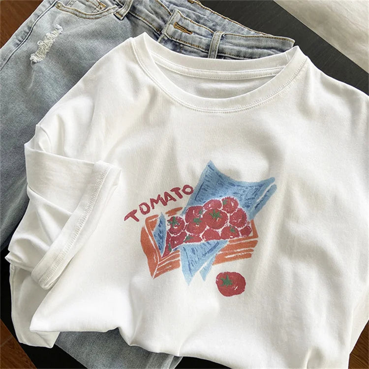 White long-sleeve shirt with tomato graphic design on a wooden surface