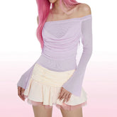 Person wearing a light purple off-shoulder top and white skirt on a pink background