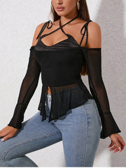 Woman wearing a black top with sheer sleeves and blue jeans on a light gray background