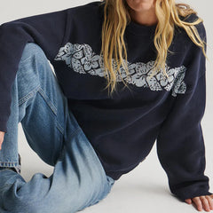Person wearing a navy blue sweater with lace detailing and light blue jeans