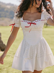 Woman wearing a white dress with red accents in an outdoor setting