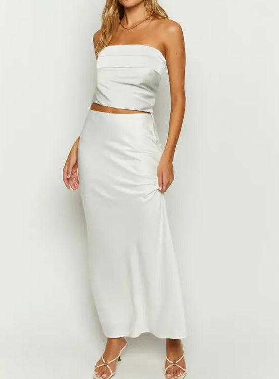 Woman wearing a white strapless top and skirt set on a plain background