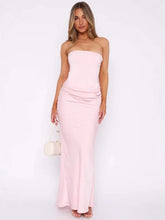Woman wearing a strapless pink gown against a white background
