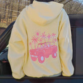 Yellow hoodie with pink graphic of a car and palm trees on a car seat.