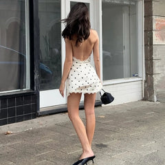 Woman in a white polka dot dress walking on a street.