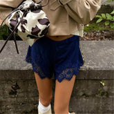 Person wearing a beige coat and blue lace shorts with a cow print bag.