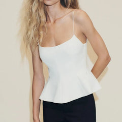 Woman wearing a white peplum top against a beige background