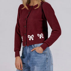 Maroon cardigan with white bow designs worn by a person
