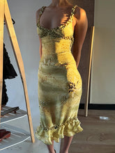 Yellow dress with floral embellishments on a mannequin against a neutral background