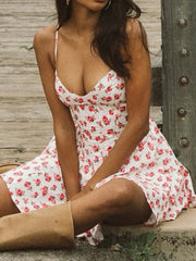 Woman wearing a white floral dress sitting outdoors.