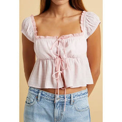 Pink ruffled top worn by a person on a beige background