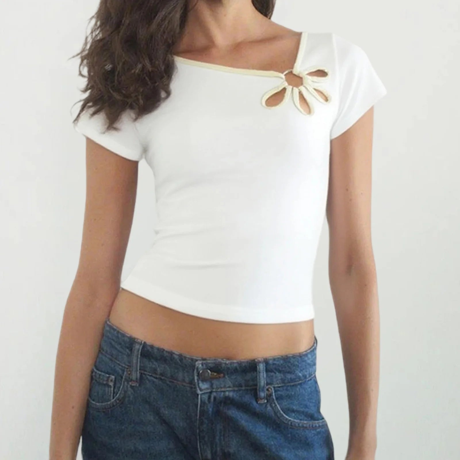 Person wearing a white crop top with a decorative bow and blue jeans