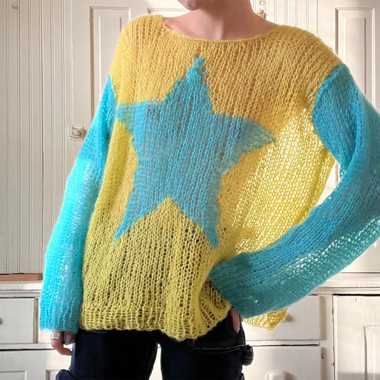 Person wearing a yellow sweater with a blue star design indoors.
