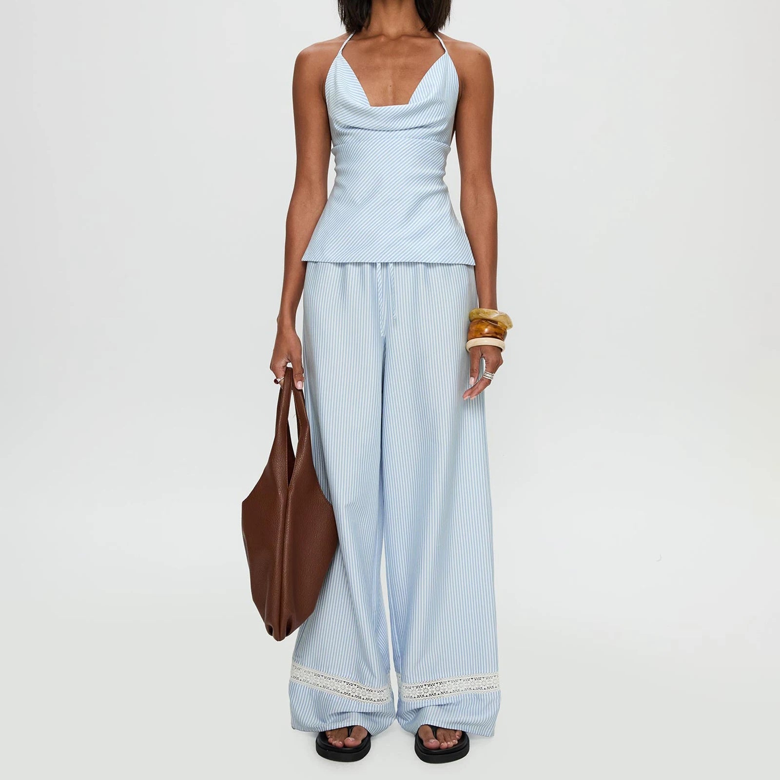 Woman wearing a light blue striped outfit holding a brown bag