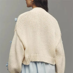 Person wearing a beige knitted cardigan against a gray background
