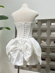 White corset-style dress on a mannequin against a geometric-patterned wall.
