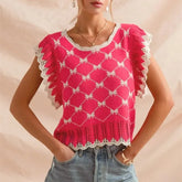 Woman wearing a pink crochet top with white trim against a beige background