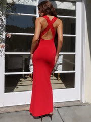 Person wearing a red dress with a backless design, standing in front of a glass door.