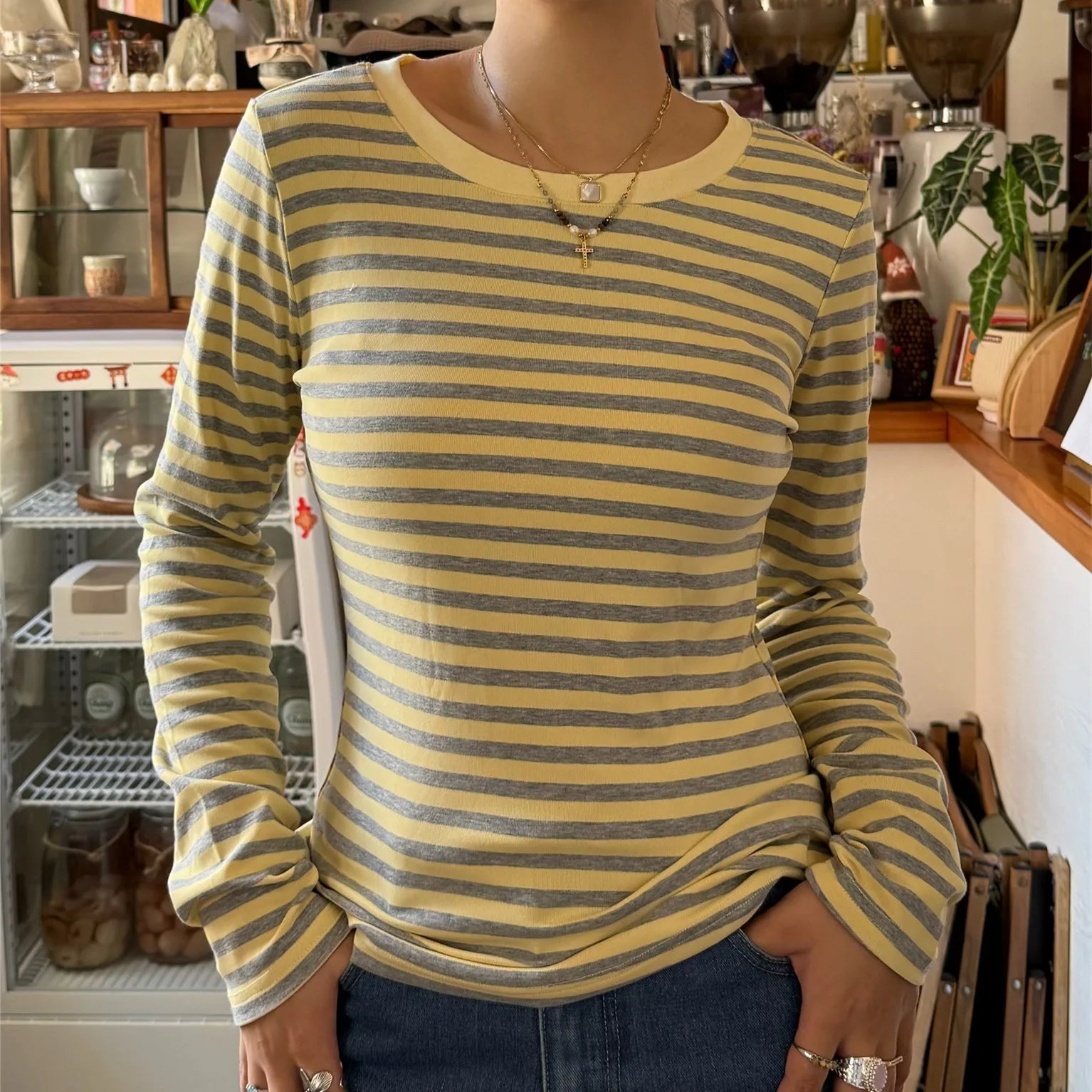 Person wearing a yellow and gray striped long-sleeve shirt in an indoor setting.