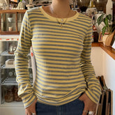 Person wearing a yellow and gray striped long-sleeve shirt in an indoor setting.