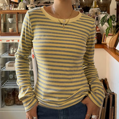 Person wearing a yellow and gray striped long-sleeve shirt in an indoor setting.