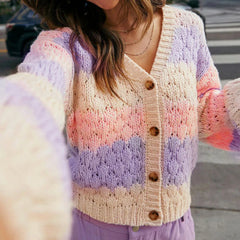 Pastel striped knitted cardigan worn by a person outdoors.