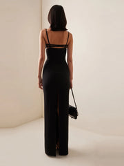 Woman wearing a black evening gown with a high slit on a plain background