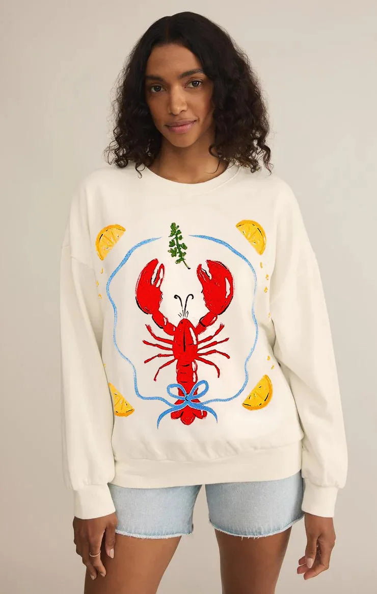 Person wearing a cream sweatshirt with a colorful lobster design