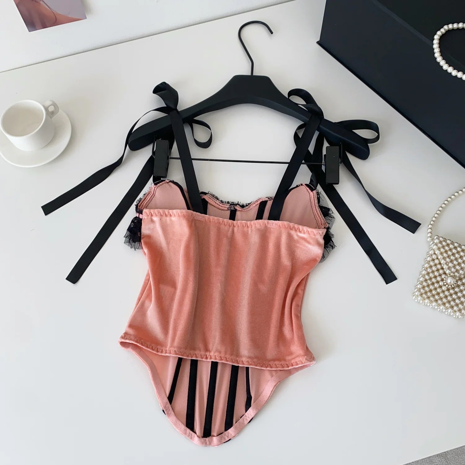Pink swimsuit with black accents on a white surface