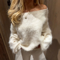 Person wearing a fluffy white sweater with a neutral background
