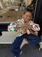 Woman sitting outdoors wearing a colorful jacket with cherry pattern