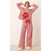 Woman wearing a red gingham pajama set with bows on a beige background