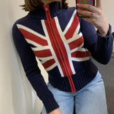 Person wearing a sweater with a Union Jack design, taking a mirror selfie.