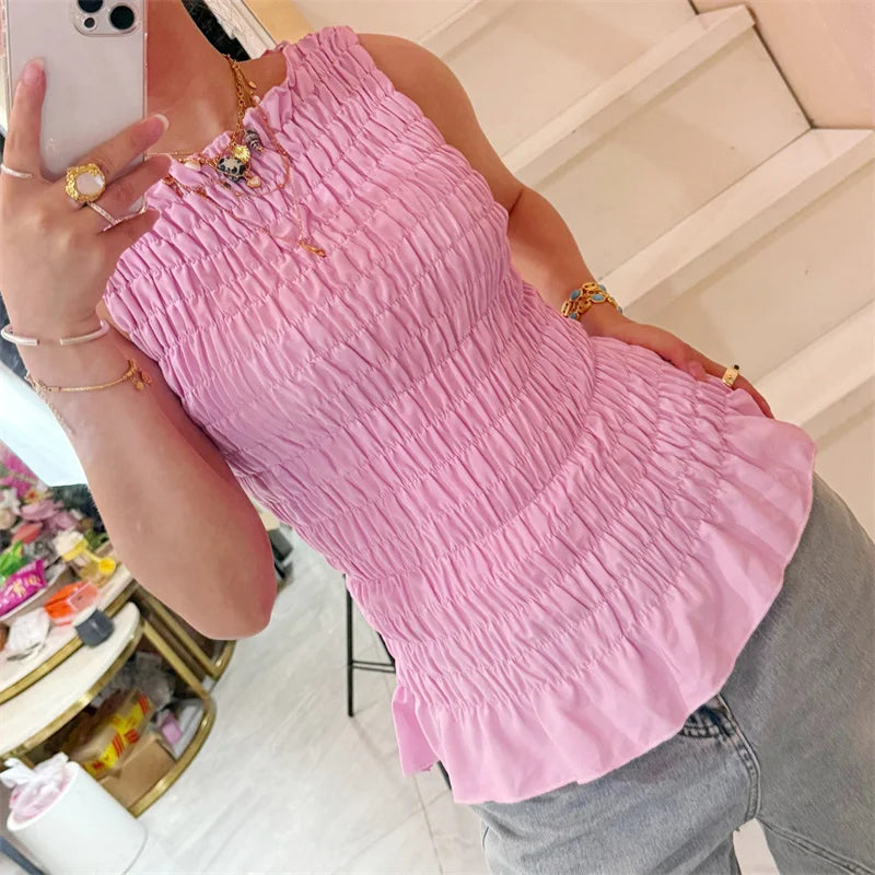 Person wearing a pink top and gray pants taking a mirror selfie.