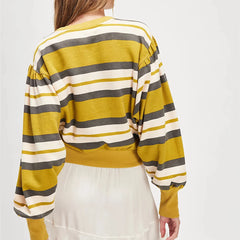 Person wearing a yellow, gray, and white striped sweater on a plain background