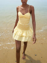Woman wearing a yellow checkered dress on a beach