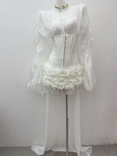 Mannequin wearing a white dress with ruffled details on a plain background