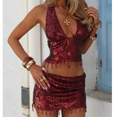 Woman wearing a red sequin outfit with gold accessories in an outdoor setting.