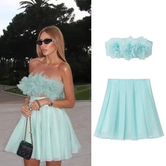 Woman wearing a light blue strapless dress with floral top and skirt, standing outdoors.