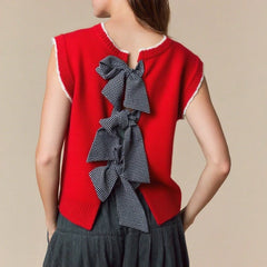 Red sleeveless sweater vest with a large bow on a beige background