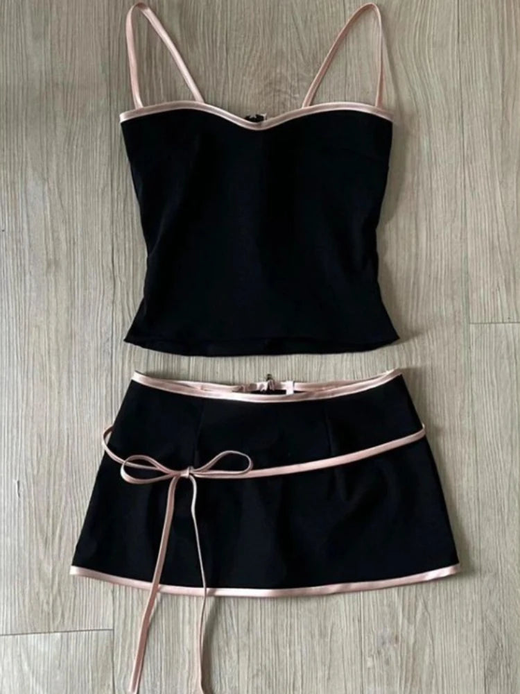 Black two-piece outfit with thin straps and a belt on a wooden surface