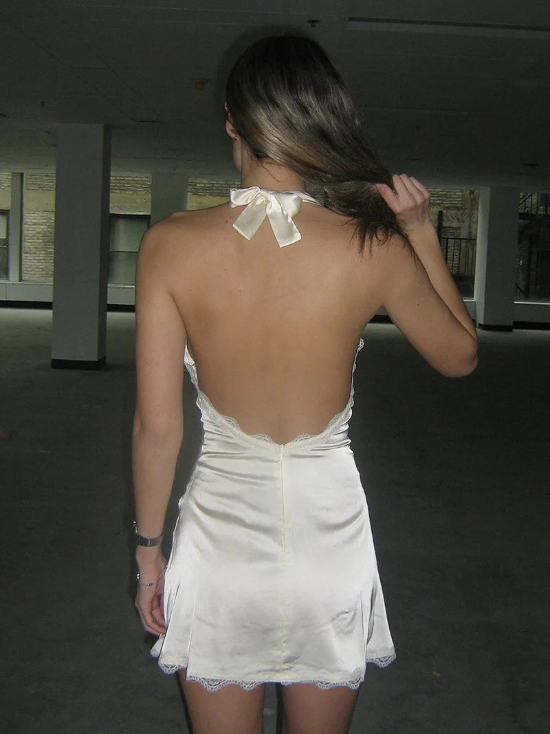 Woman wearing a white dress with a bow at the neck in an indoor setting