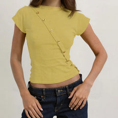 Person wearing a mustard yellow top with button details and dark blue jeans on a plain background
