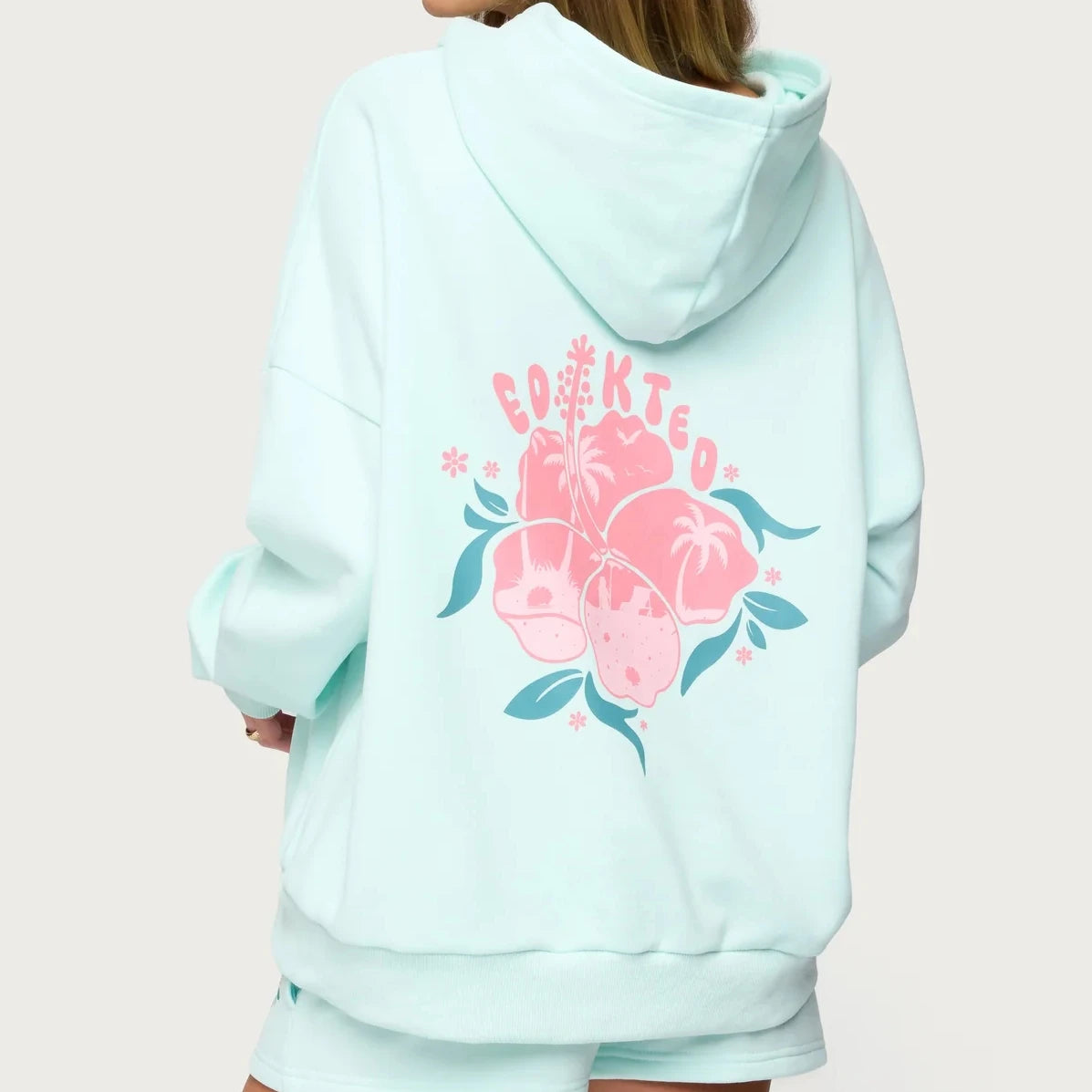 Light blue hoodie with floral design and text on the back against a light pink background