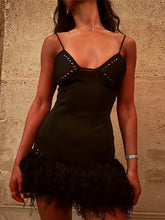 Black dress with intricate detailing on a textured wall background