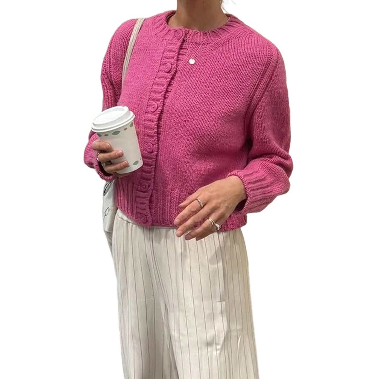 Person wearing a pink knitted cardigan holding a coffee cup