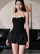 Woman wearing a black dress with white lace trim in an indoor setting.